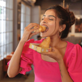 A woman eating a piece of snack item